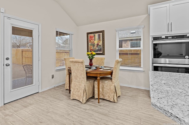 dining space with light hardwood / wood-style floors and vaulted ceiling