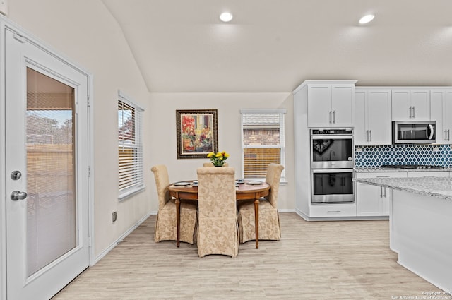 kitchen with white cabinetry, appliances with stainless steel finishes, light stone counters, and light wood-type flooring