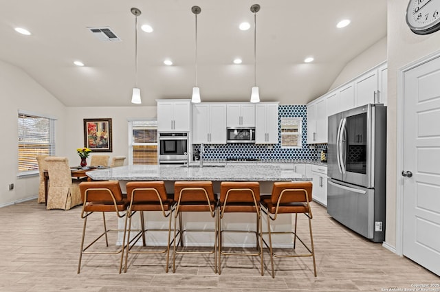 kitchen with light stone counters, stainless steel appliances, and an island with sink