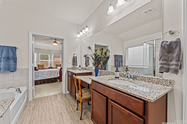 bathroom featuring a tub to relax in, lofted ceiling, wood-type flooring, vanity, and ceiling fan