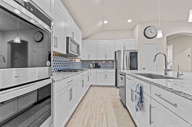 kitchen featuring pendant lighting, sink, white cabinetry, stainless steel appliances, and light stone countertops