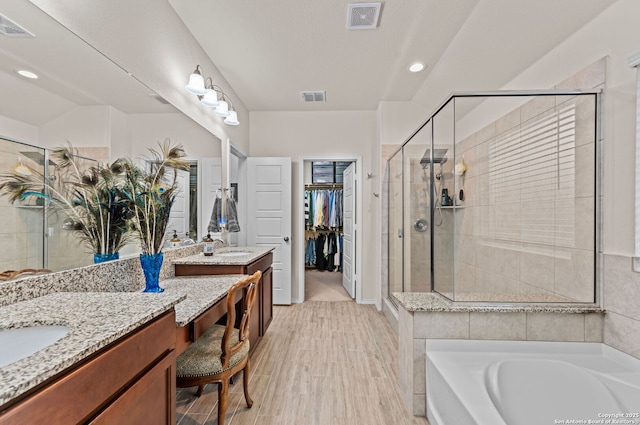 bathroom featuring hardwood / wood-style flooring, vanity, and plus walk in shower