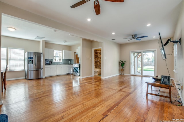 living room with ceiling fan, a healthy amount of sunlight, sink, and light hardwood / wood-style floors