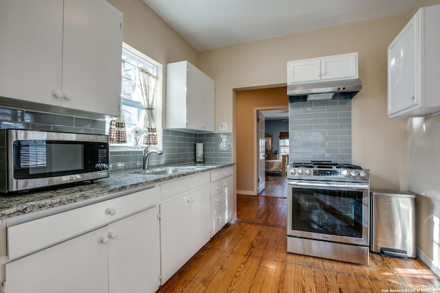 kitchen featuring light stone counters, stainless steel appliances, sink, and white cabinets