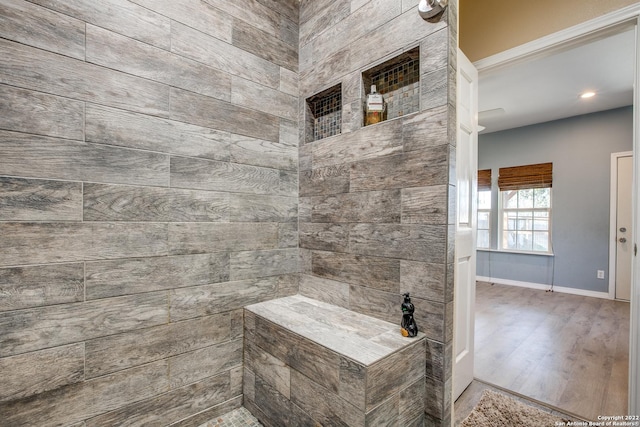 bathroom with tiled shower and wood-type flooring