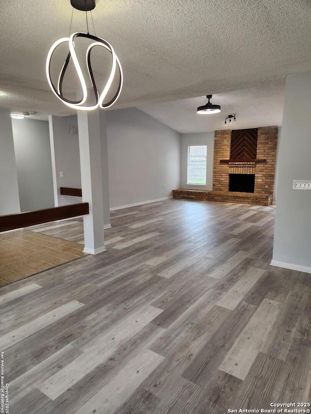 unfurnished living room with hardwood / wood-style floors, a brick fireplace, and a textured ceiling