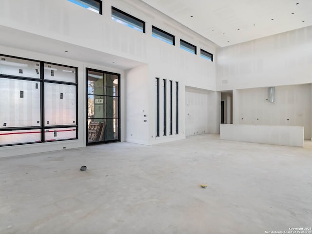 unfurnished living room featuring a towering ceiling