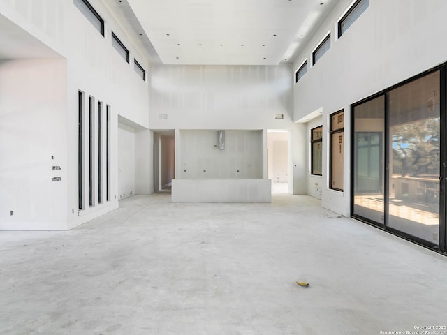 unfurnished living room with a towering ceiling and a wealth of natural light