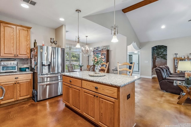 kitchen featuring light stone counters, an inviting chandelier, decorative light fixtures, stainless steel fridge, and a kitchen island