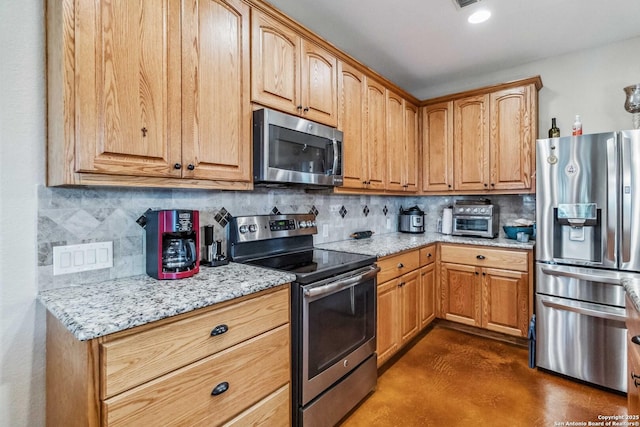 kitchen featuring appliances with stainless steel finishes, light stone countertops, and decorative backsplash