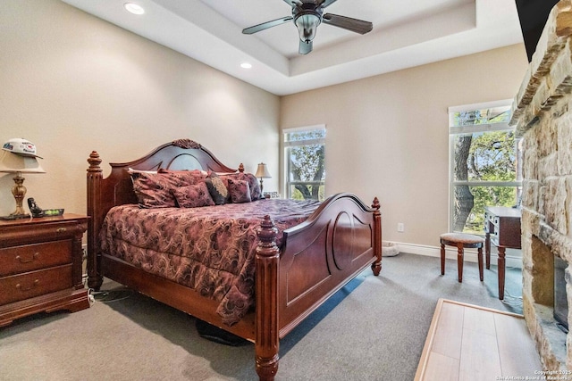 carpeted bedroom with ceiling fan and a tray ceiling