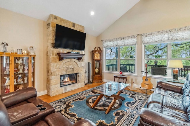 living room with hardwood / wood-style flooring, vaulted ceiling, and a stone fireplace