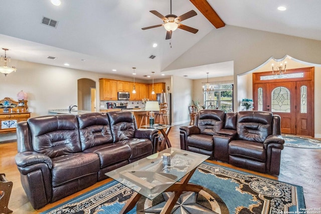 living room with ceiling fan with notable chandelier, beam ceiling, and high vaulted ceiling