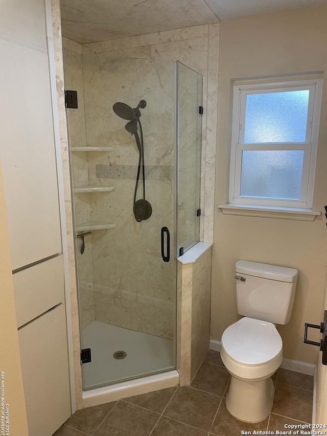 bathroom featuring a shower with shower door, tile patterned floors, and toilet