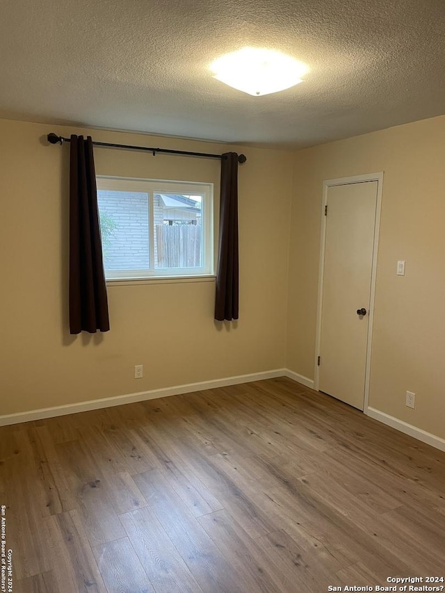 empty room featuring light hardwood / wood-style flooring and a textured ceiling