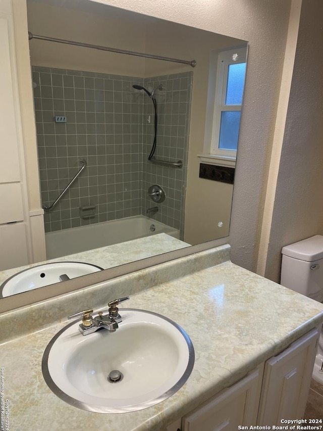 full bathroom featuring tiled shower / bath, vanity, and toilet