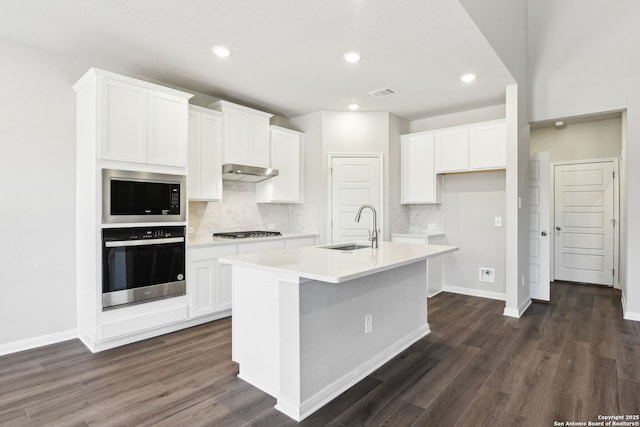 kitchen featuring visible vents, a kitchen island with sink, a sink, under cabinet range hood, and appliances with stainless steel finishes