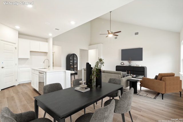 dining space featuring high vaulted ceiling, sink, and light hardwood / wood-style floors