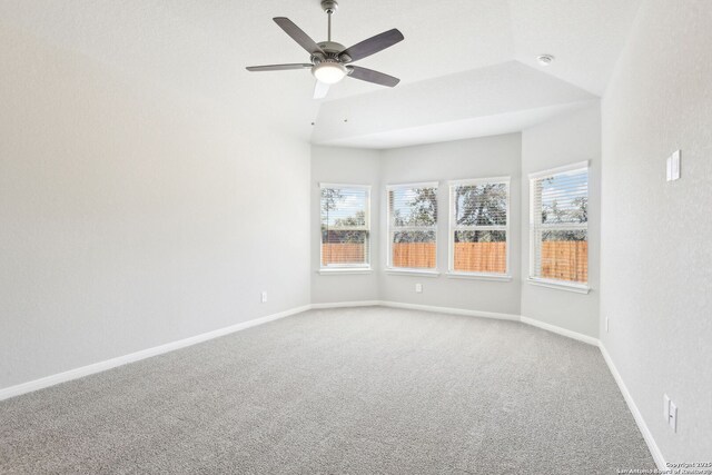 carpeted empty room with a wealth of natural light, baseboards, lofted ceiling, and a ceiling fan