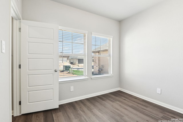 unfurnished room featuring baseboards and dark wood-type flooring