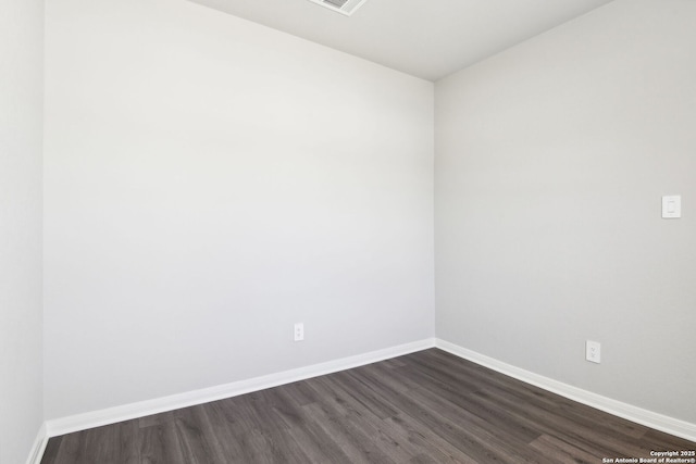 spare room with visible vents, baseboards, and dark wood-type flooring