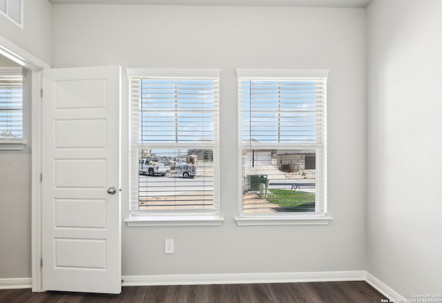 spare room featuring visible vents, dark wood-style floors, and baseboards