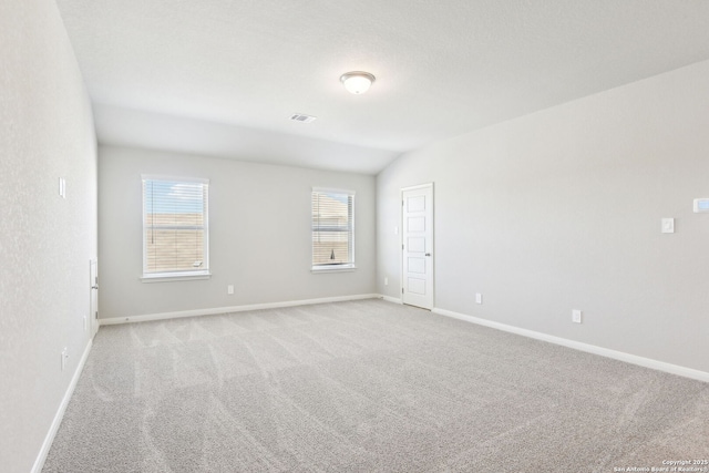 empty room featuring baseboards, visible vents, and light carpet