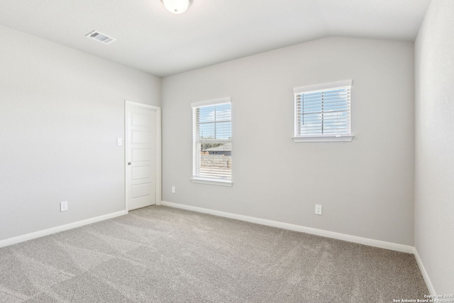 spare room with visible vents, lofted ceiling, baseboards, and carpet floors