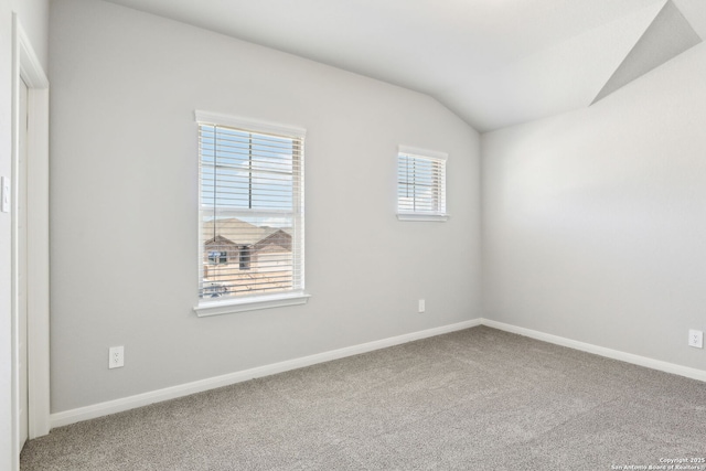 spare room featuring vaulted ceiling, carpet, and baseboards