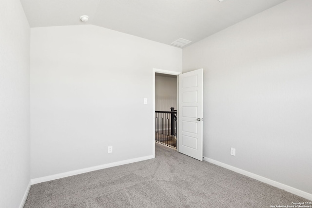 spare room with vaulted ceiling, baseboards, and carpet floors