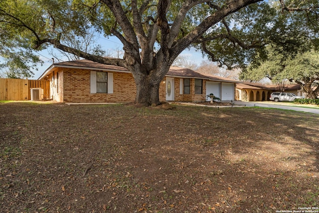 ranch-style home with a carport, a garage, and central AC unit