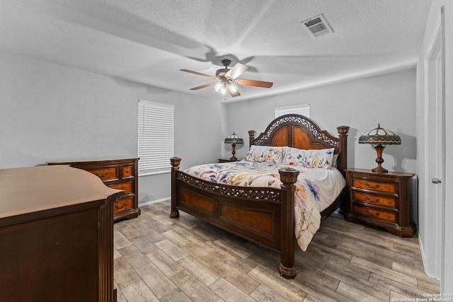 bedroom with ceiling fan, light hardwood / wood-style floors, and a textured ceiling