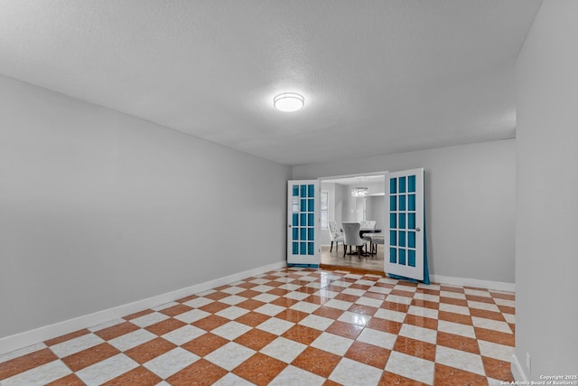 unfurnished room with a textured ceiling and french doors