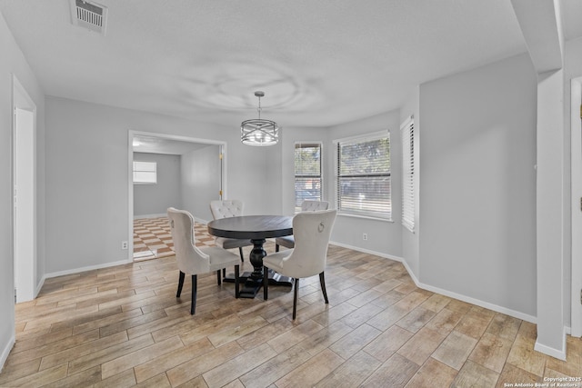 dining area with light hardwood / wood-style floors and a notable chandelier