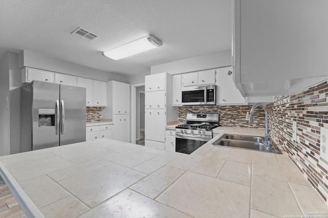 kitchen with sink, tile countertops, stainless steel appliances, and white cabinets