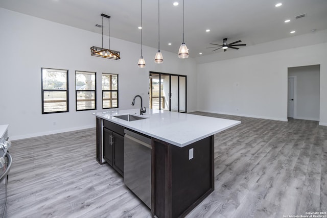 kitchen with pendant lighting, dishwasher, sink, light hardwood / wood-style floors, and a center island with sink