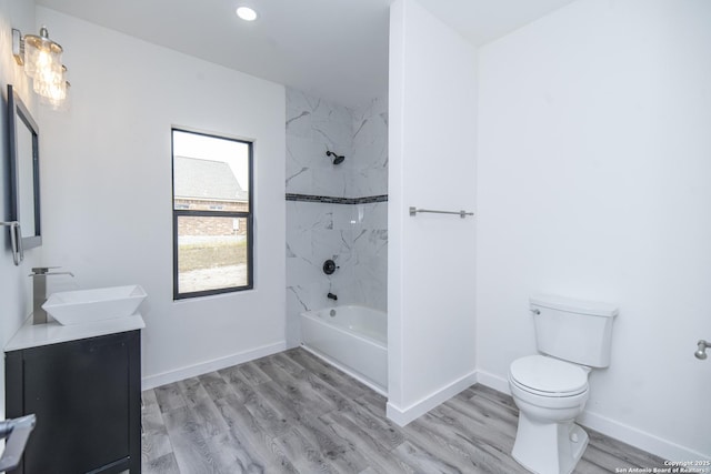 full bathroom featuring tiled shower / bath combo, vanity, hardwood / wood-style flooring, and toilet