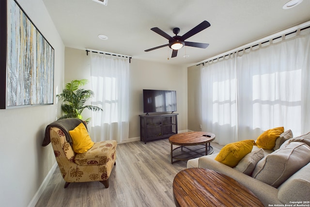living room with plenty of natural light, ceiling fan, and light hardwood / wood-style flooring