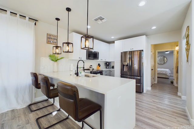 kitchen with white cabinetry, sink, hanging light fixtures, kitchen peninsula, and stainless steel appliances