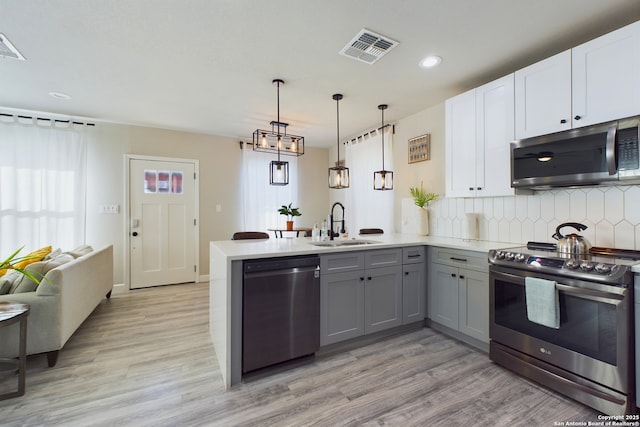 kitchen featuring sink, gray cabinetry, kitchen peninsula, stainless steel appliances, and white cabinets