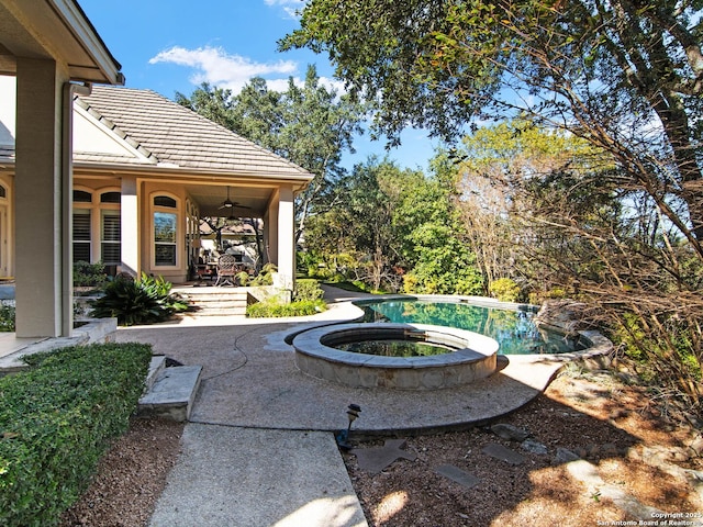 view of patio / terrace with a swimming pool with hot tub and ceiling fan