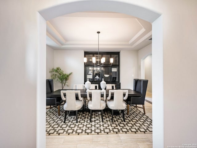 dining room with a notable chandelier and a tray ceiling