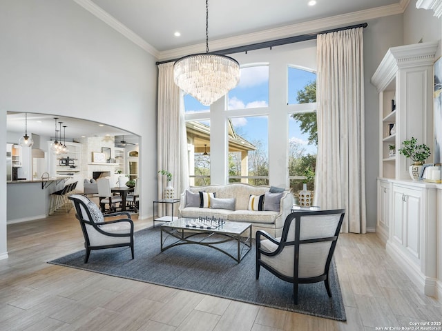 living room with plenty of natural light, ornamental molding, light hardwood / wood-style floors, and a high ceiling