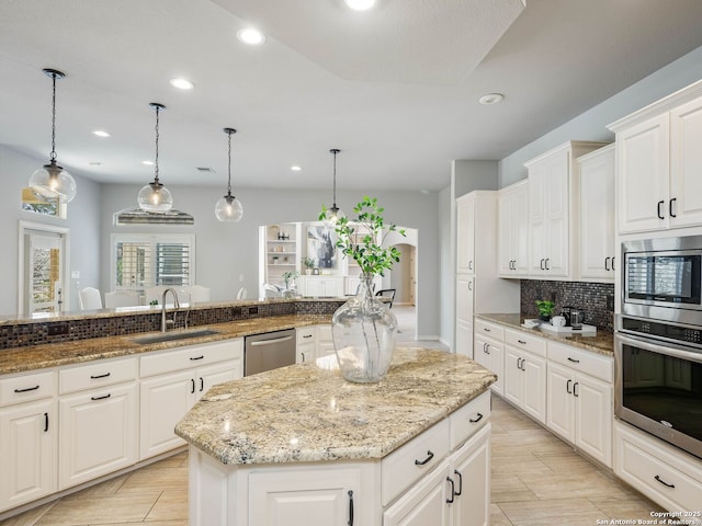 kitchen with pendant lighting, sink, white cabinets, a center island, and stainless steel appliances