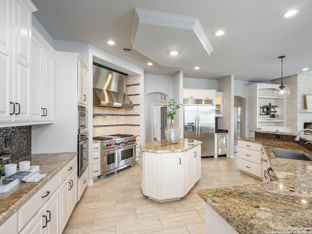 kitchen with sink, hanging light fixtures, high end appliances, a center island, and wall chimney exhaust hood