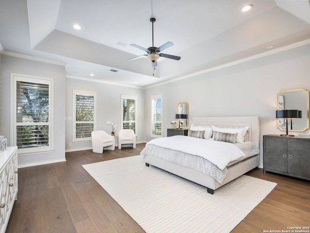 bedroom with dark wood-type flooring, ceiling fan, a tray ceiling, and crown molding