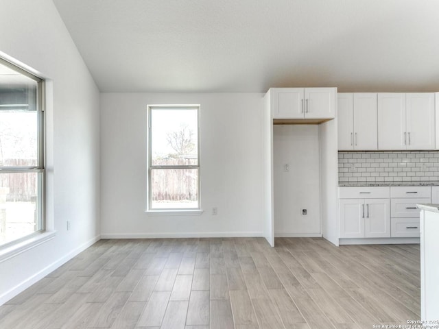 kitchen featuring backsplash, light hardwood / wood-style flooring, and white cabinets