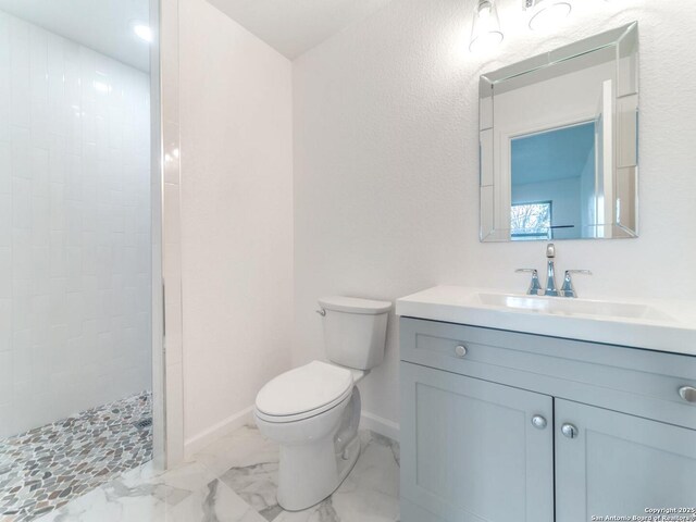 bathroom with vanity, tiled shower, and toilet