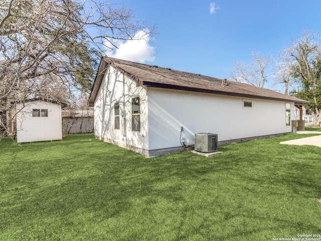 view of side of property with a shed, central AC, and a lawn