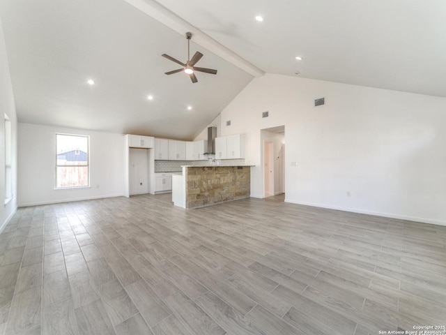 unfurnished living room featuring high vaulted ceiling, beam ceiling, light hardwood / wood-style floors, and ceiling fan